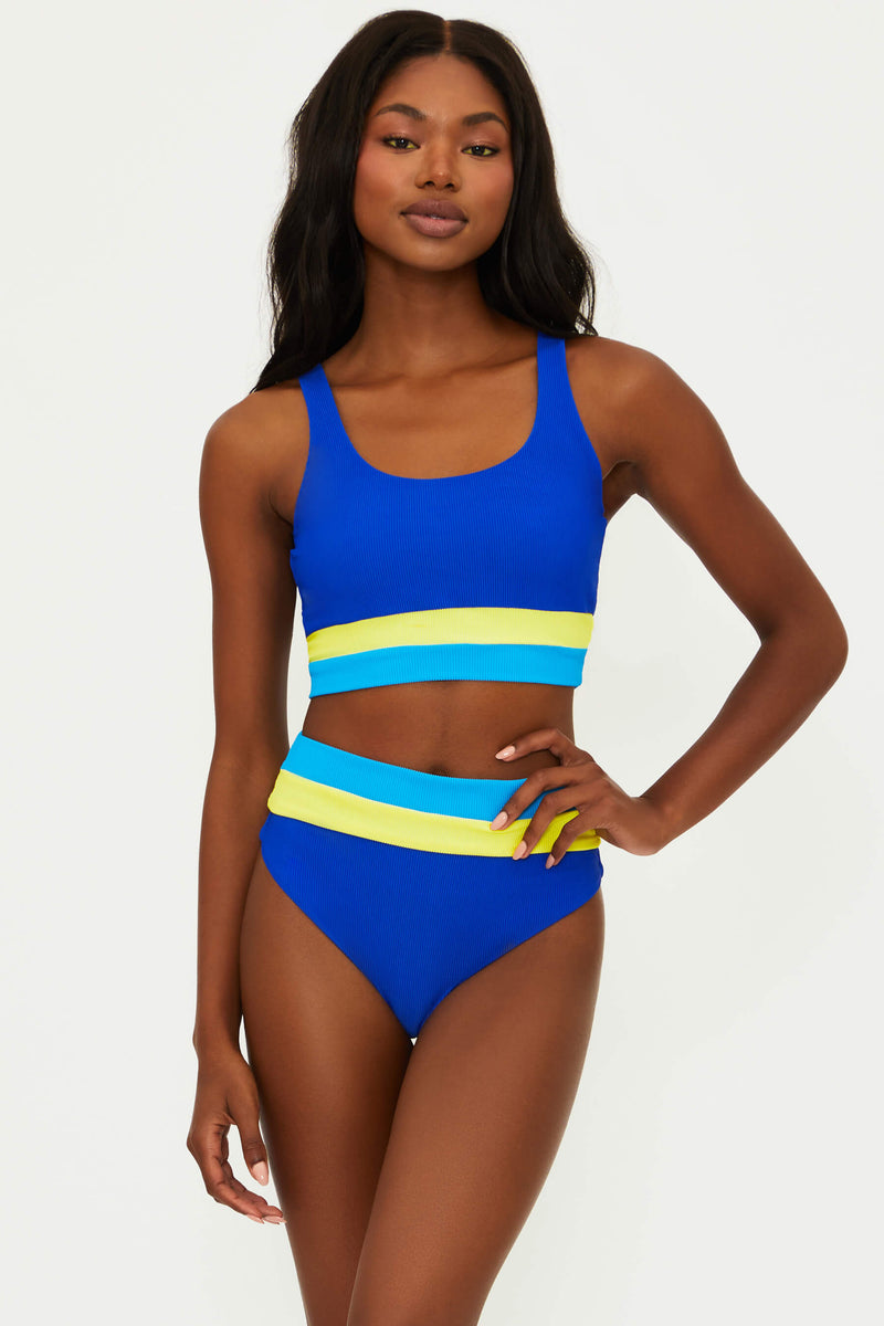 A model wearing a blue and multicolored ribbed swim top with fixed straps and a scoop neck.