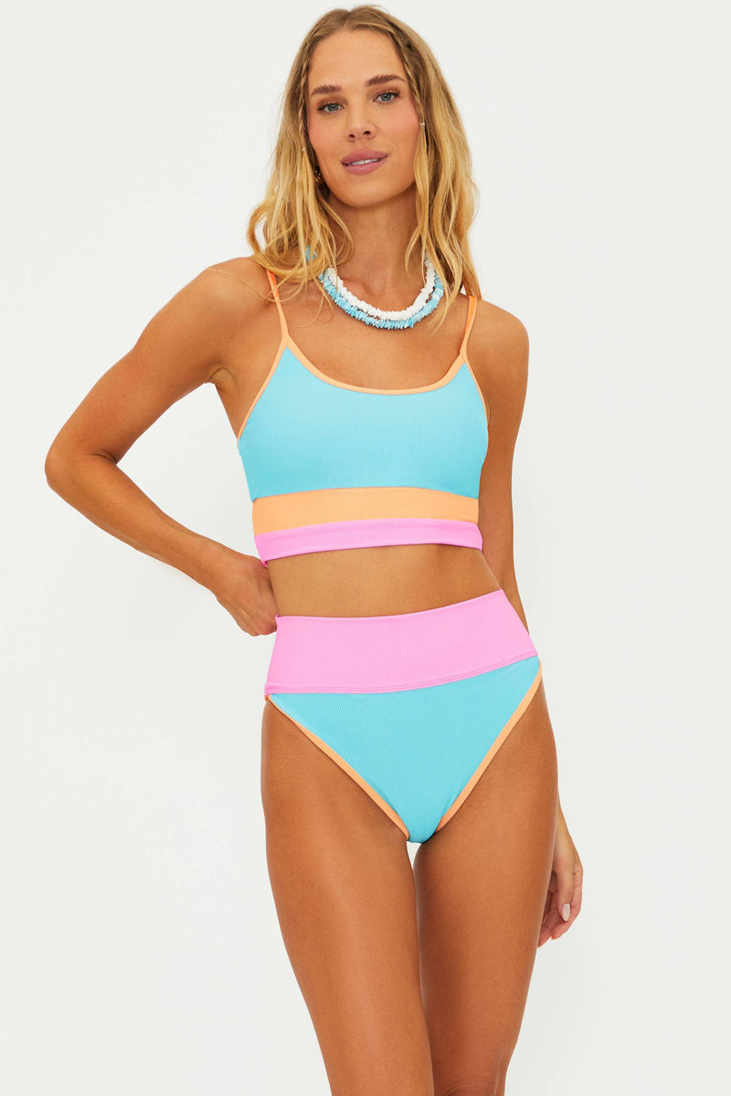 A model wearing a colorblock swim top in blue, pink, and orange with matching high-waisted bottoms.