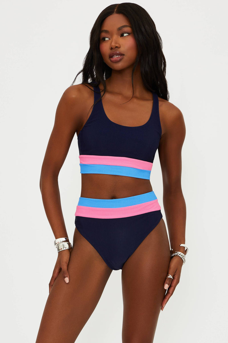 Woman wearing a navy blue bikini with pink and blue stripes on a white background