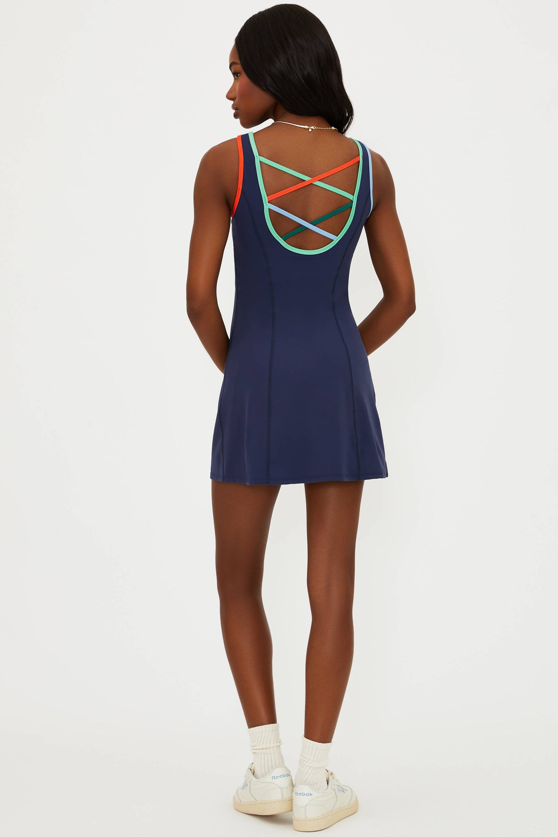 Woman wearing a navy blue dress with colorful criss-cross back design on a white background