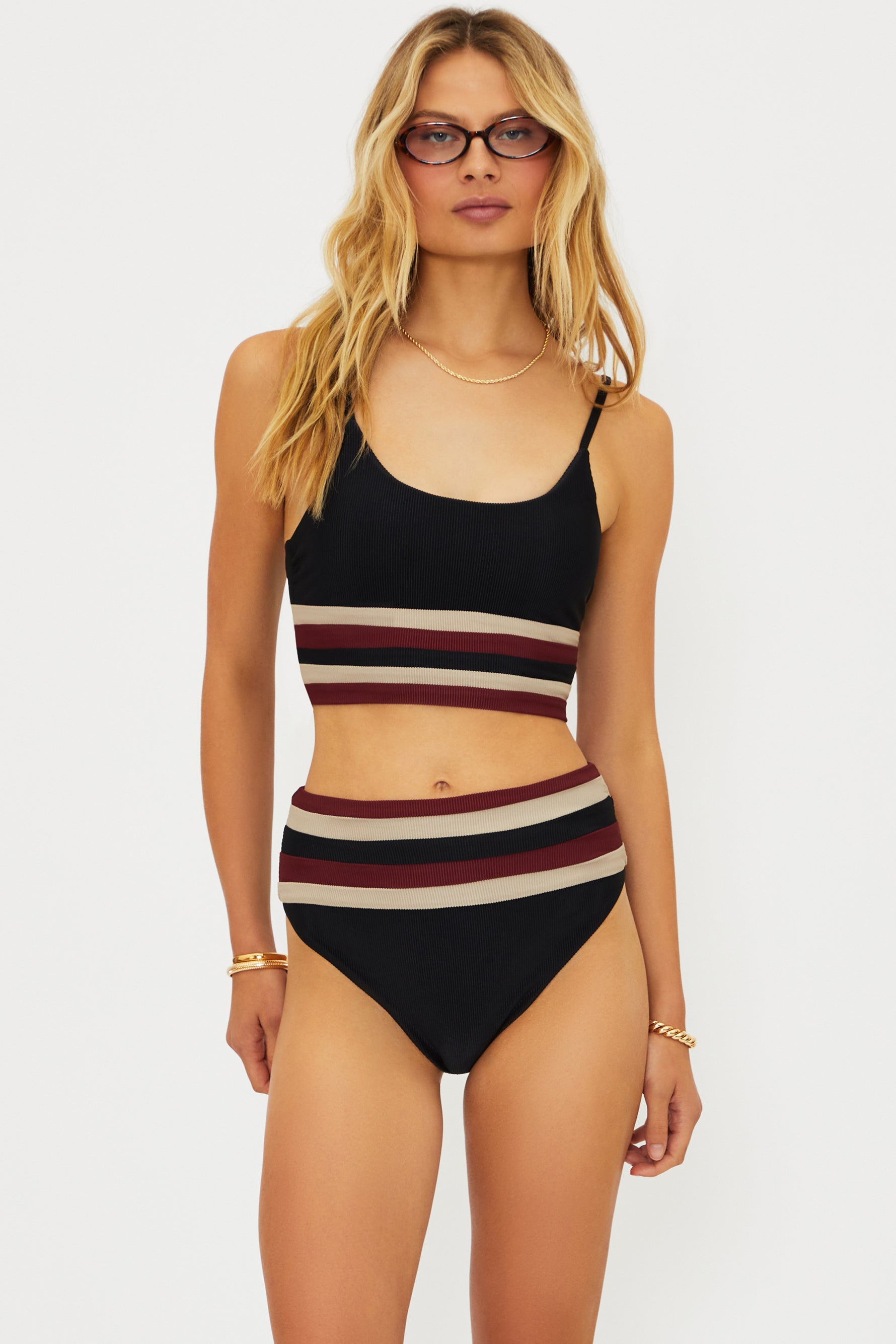 Woman wearing a striped black, red, and beige bikini set on a white background