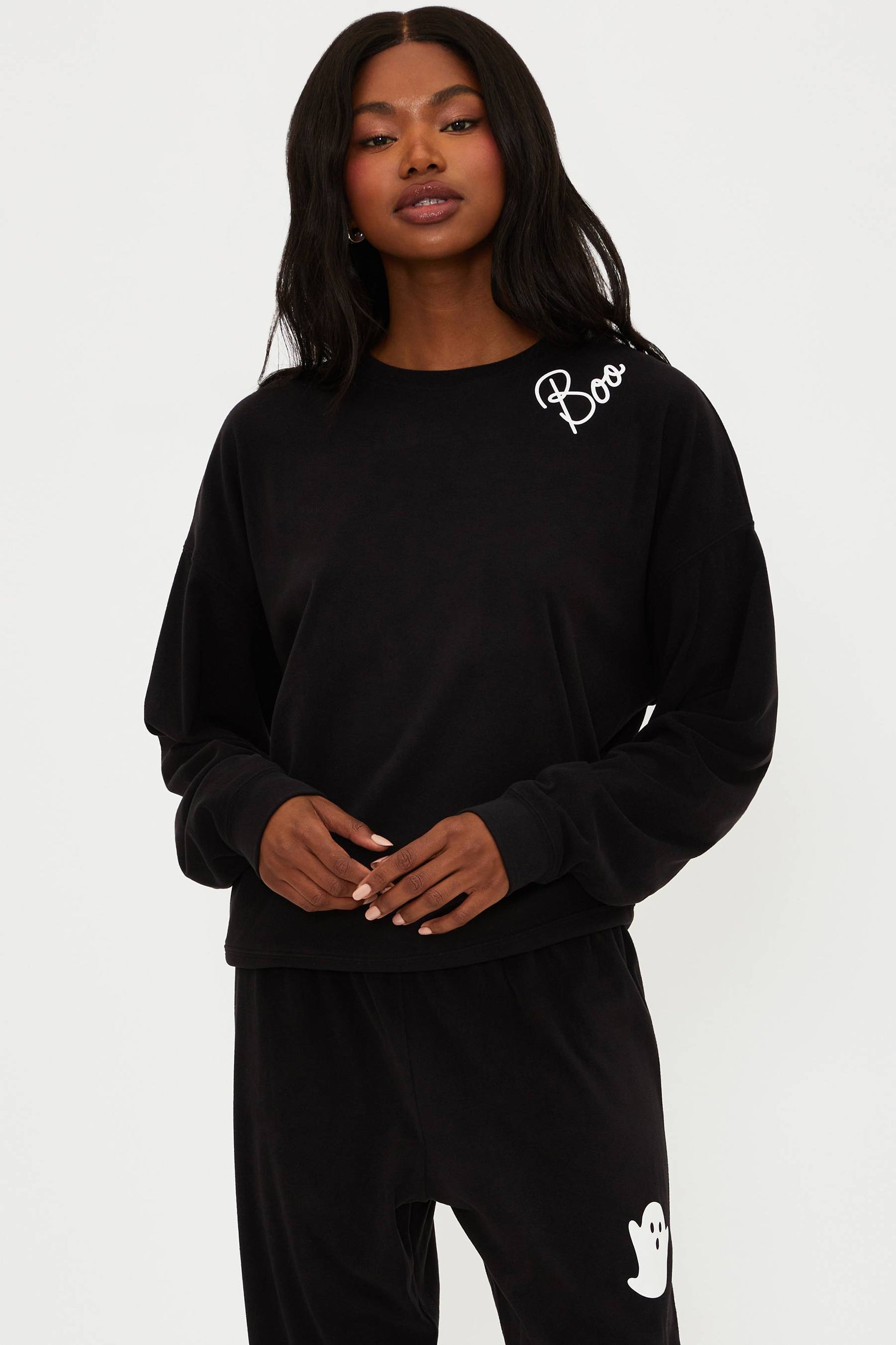Person wearing a black outfit with white branding on a white background