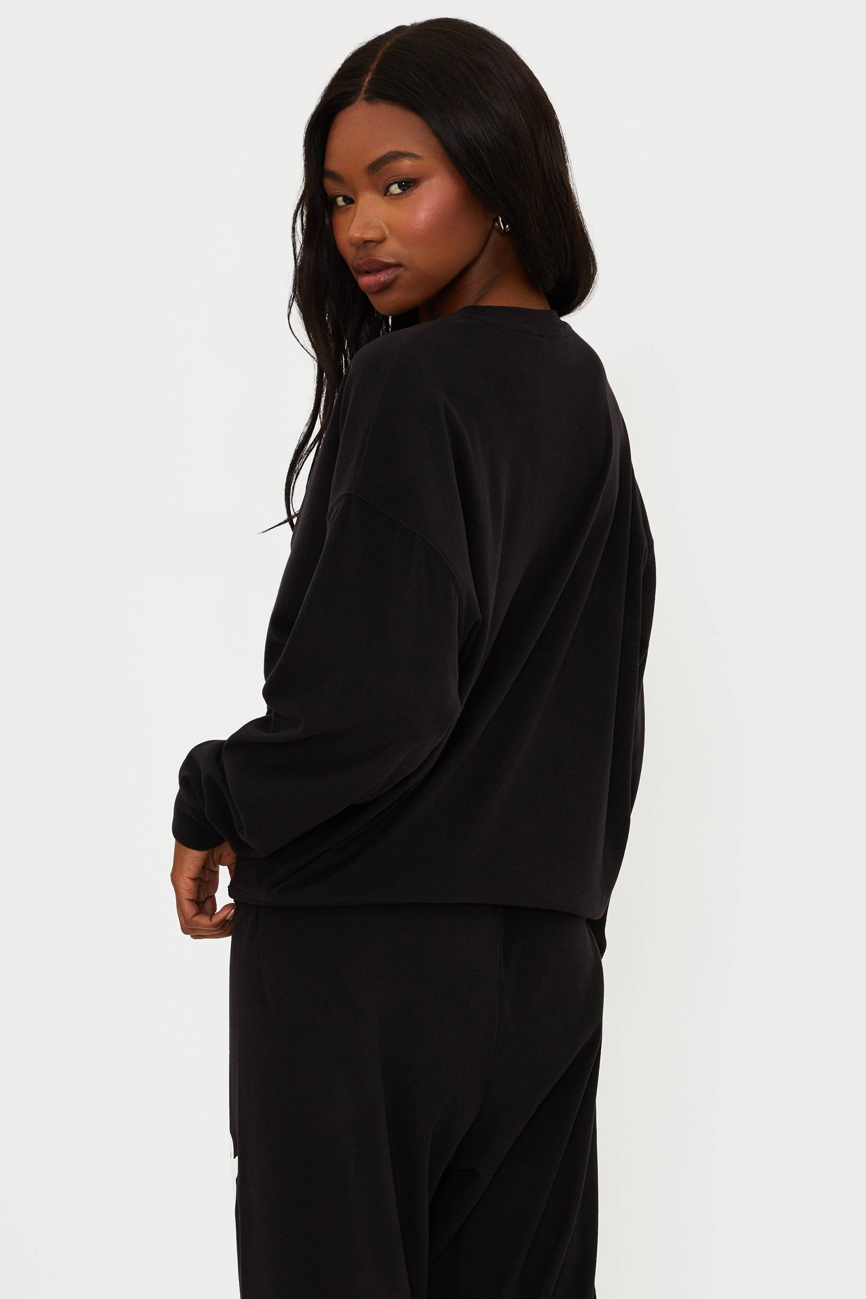 Person wearing a black outfit with white branding on a white background