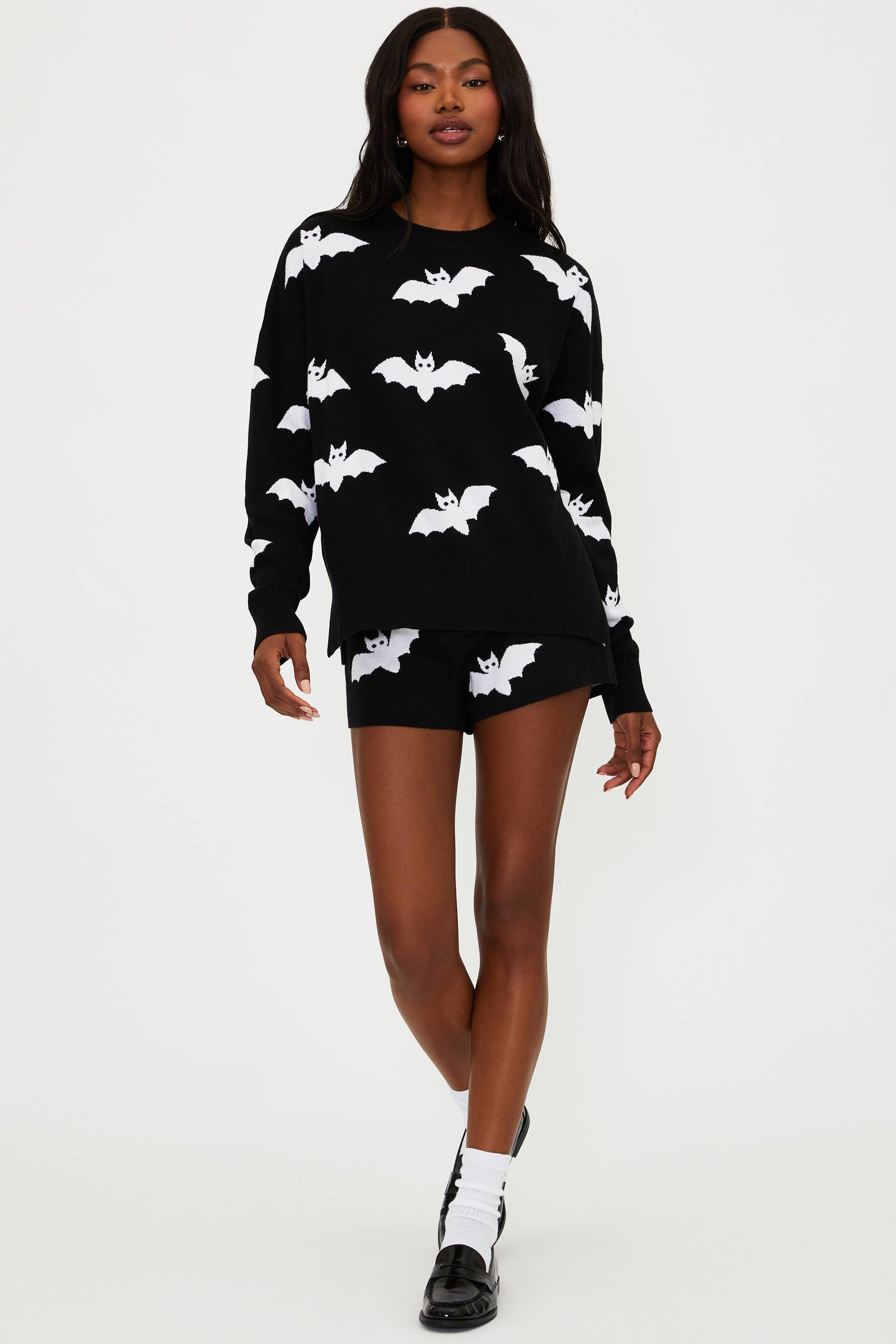 Woman wearing a black sweater with white bat patterns on a white background