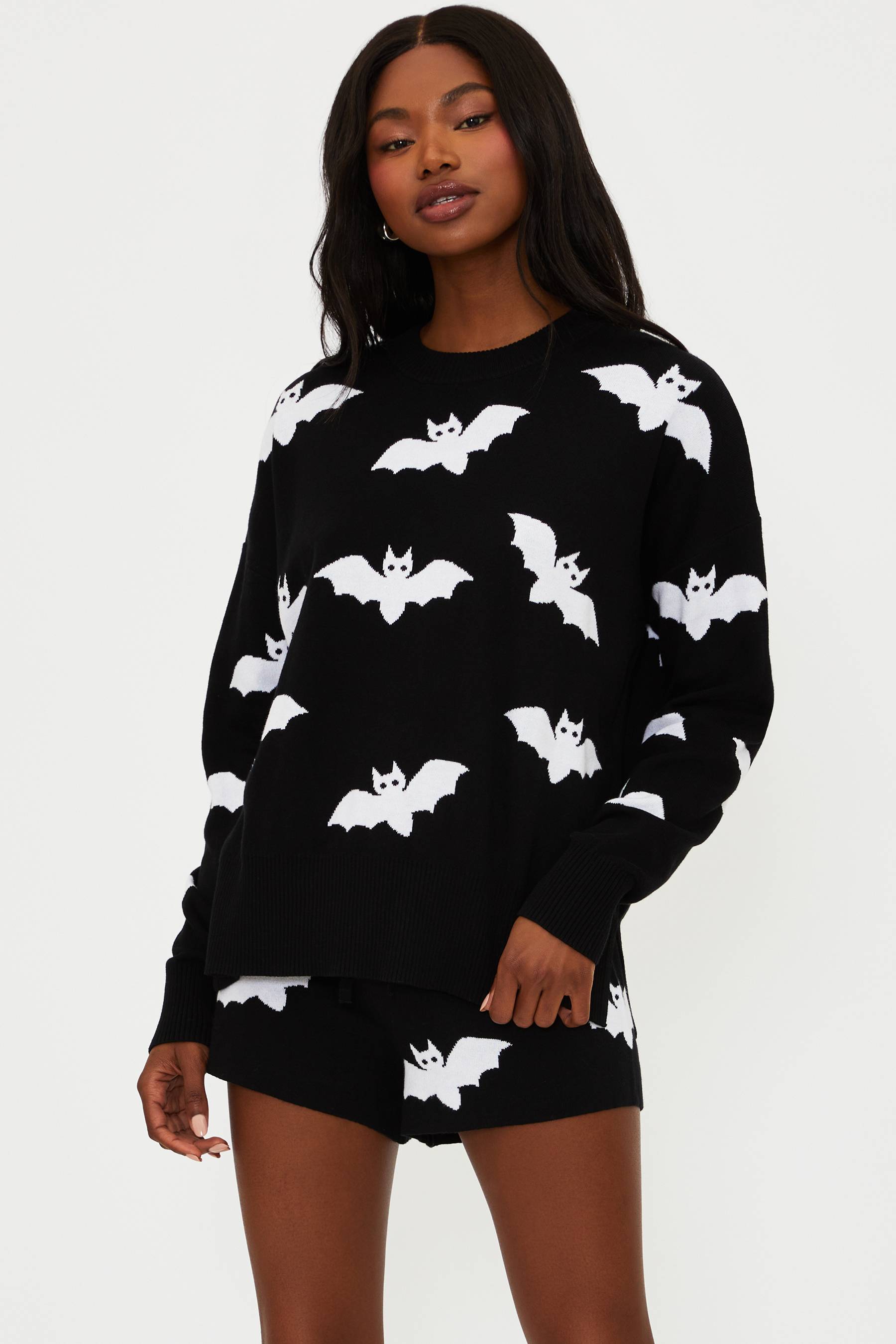 Woman wearing a black outfit with white bat patterns on a plain background