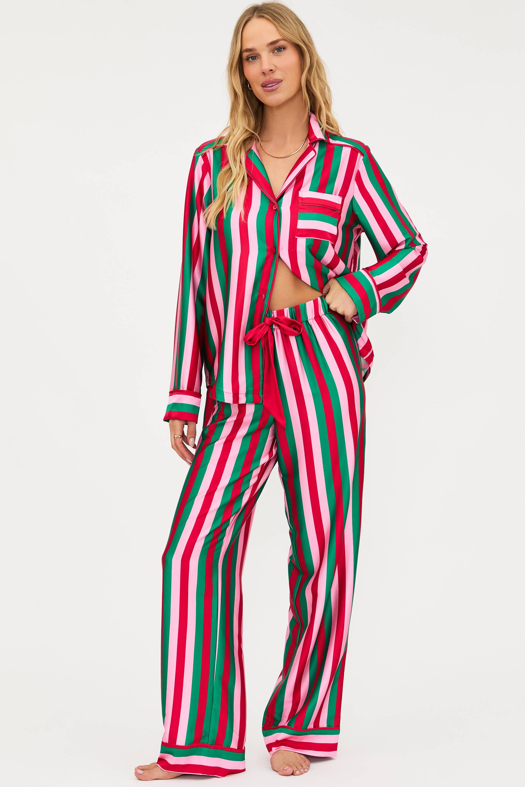 Woman wearing a red, green, and white striped pajama set on a white background