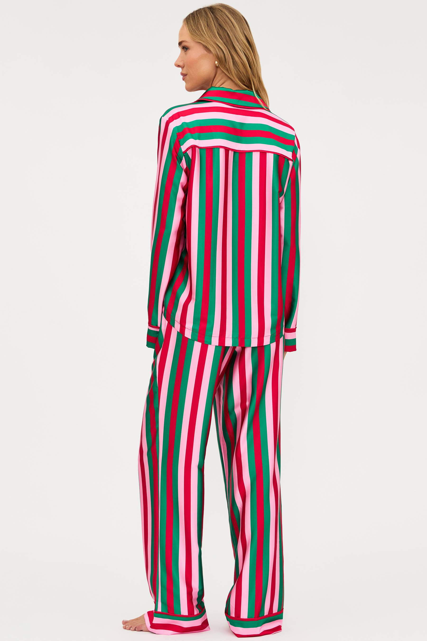 Woman wearing a red, green, and pink striped pajama set on a white background