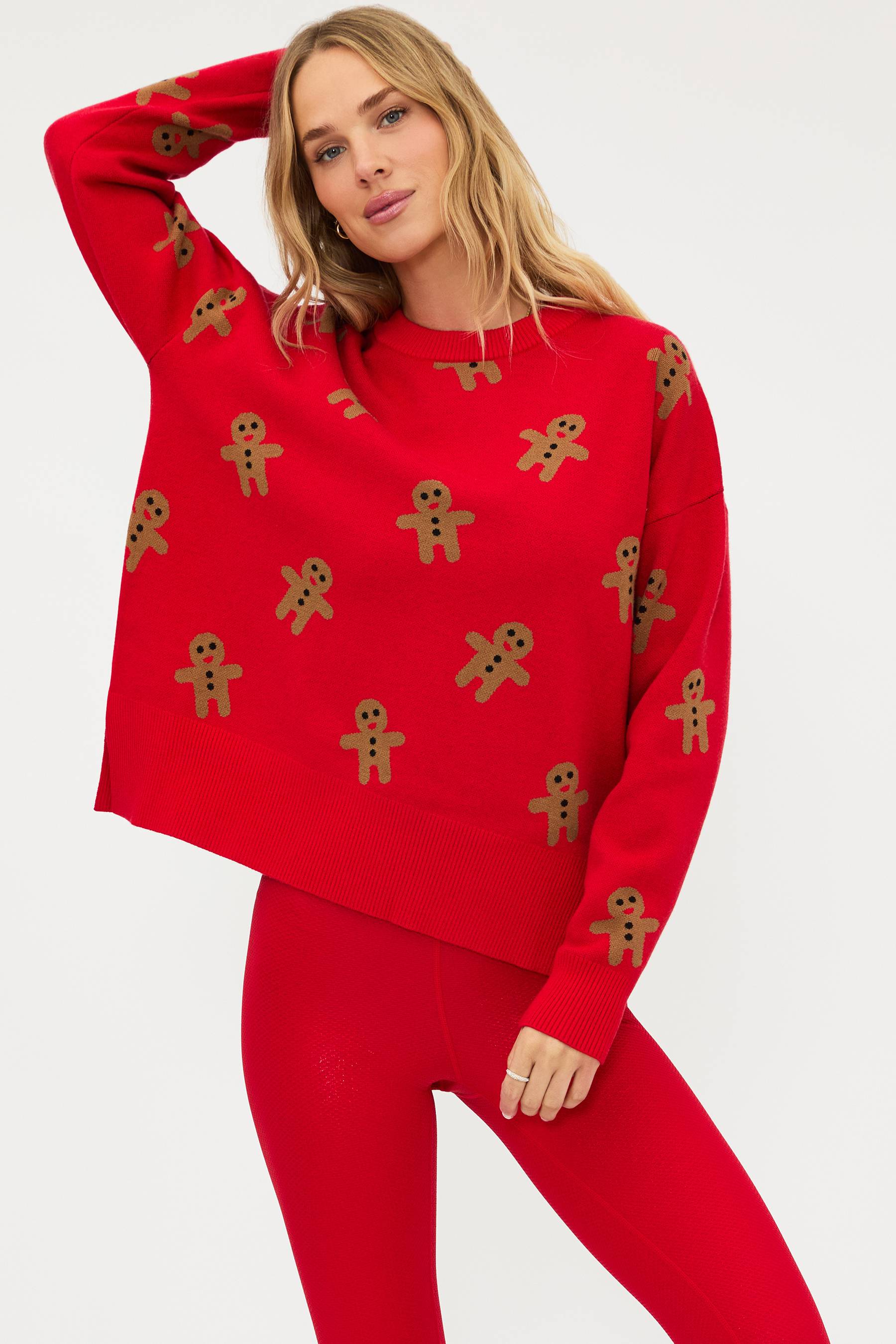 Woman wearing a red sweater with gingerbread man patterns on a white background