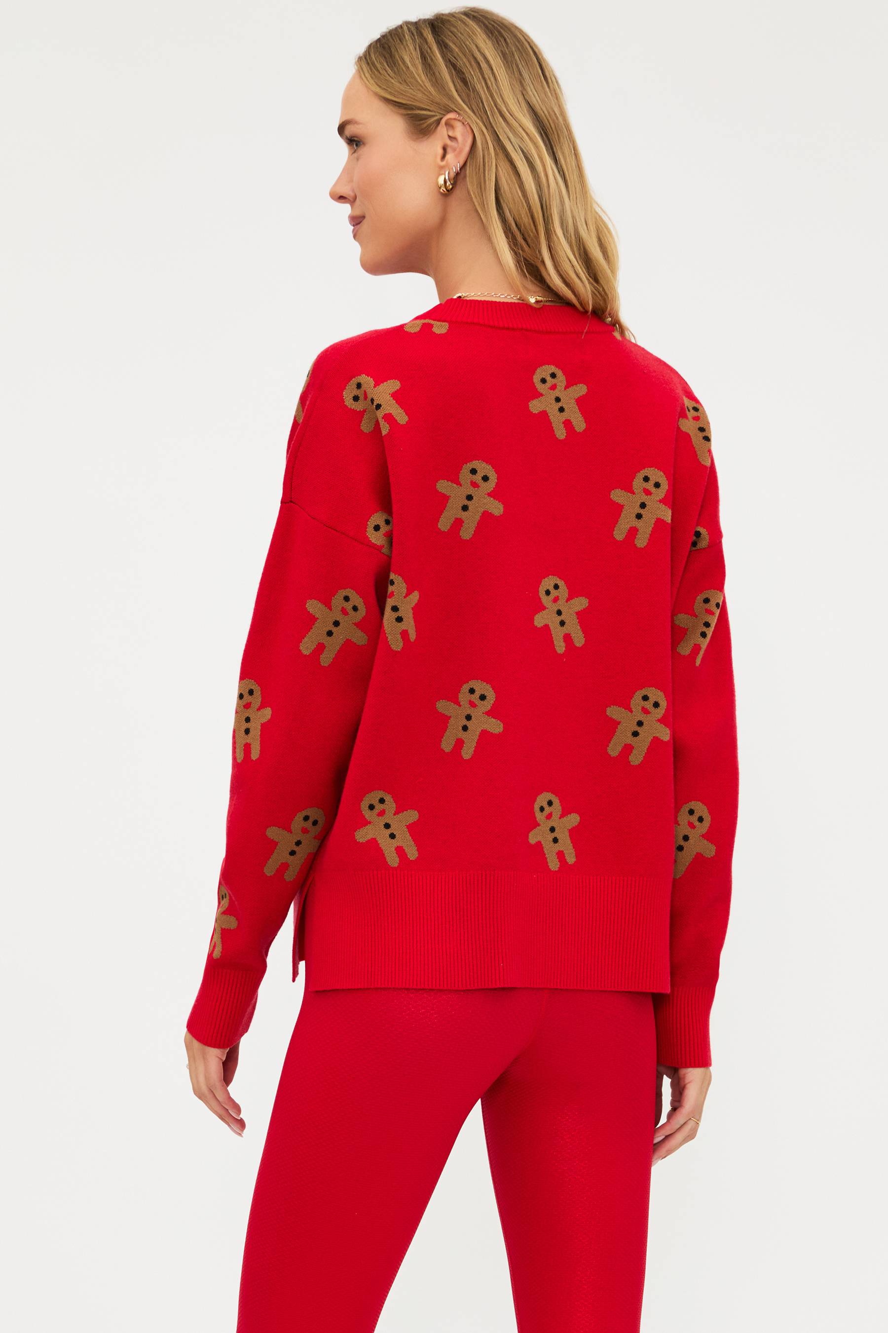 Red sweater with gingerbread man pattern worn by a person on a white background