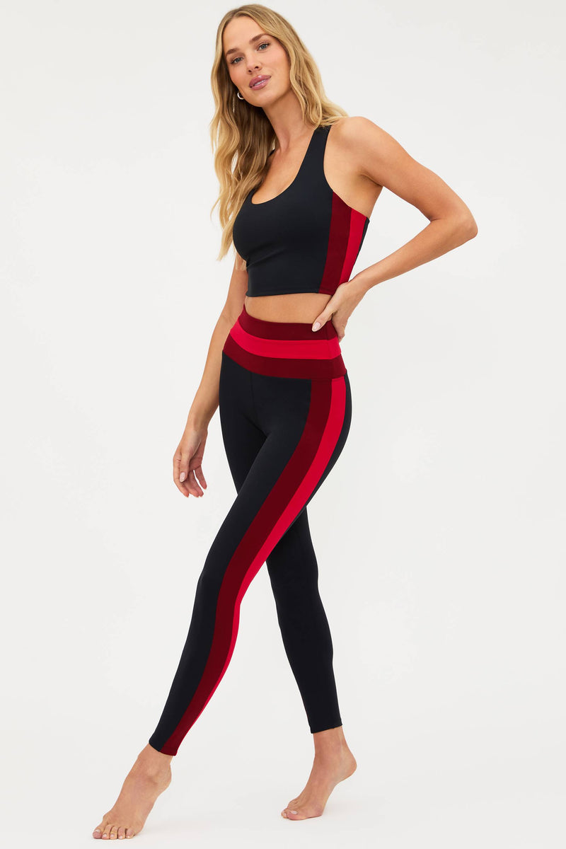 Woman wearing a black and red athletic outfit on a white background