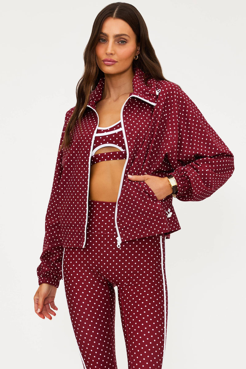 Woman wearing a burgundy polka dot tracksuit on a white background