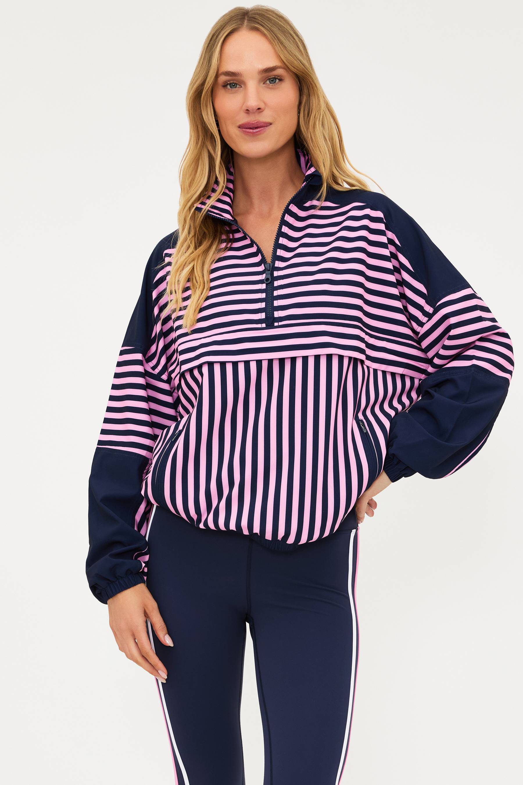 Woman wearing a striped shirt and navy pants on a white background