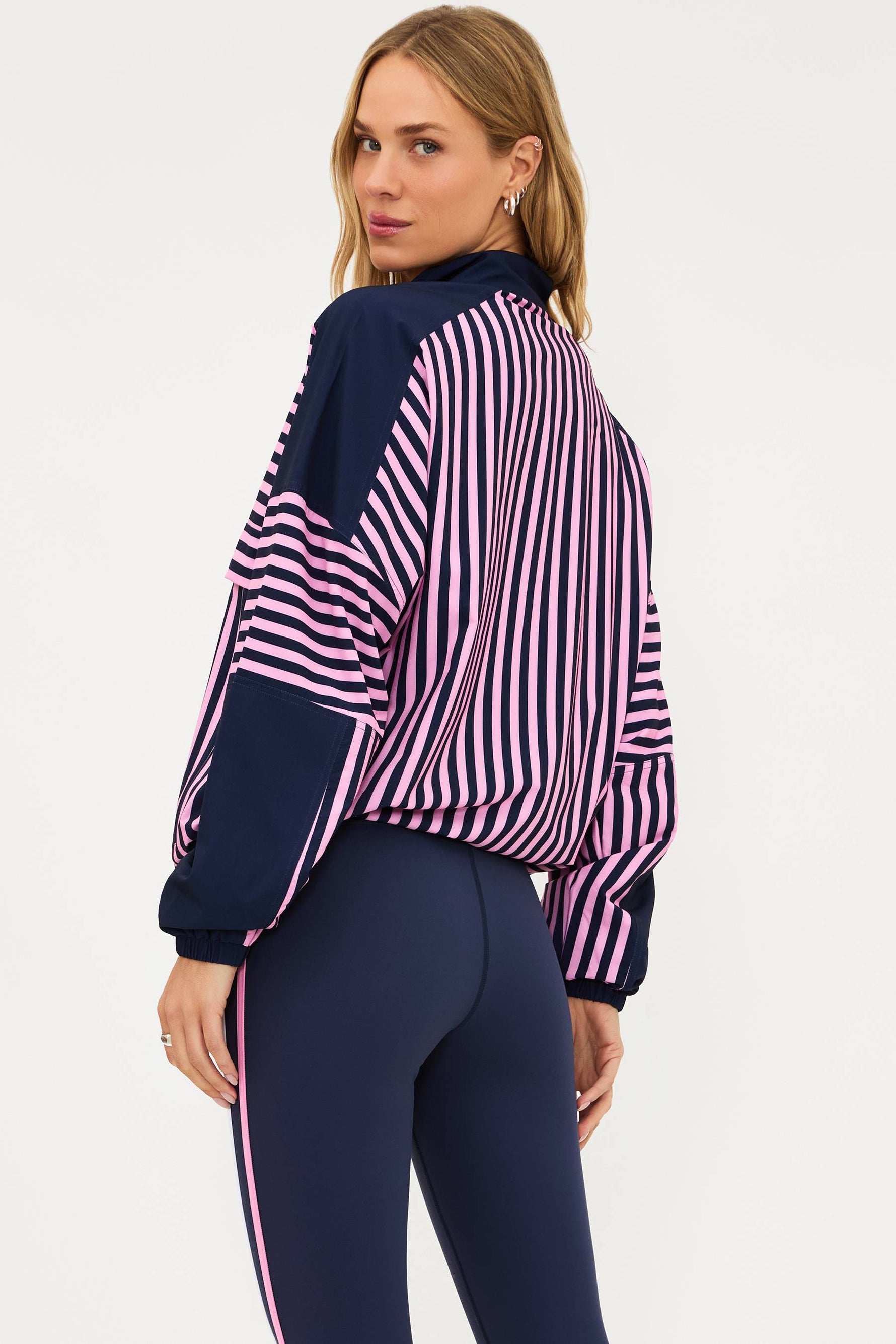 Woman wearing a navy and pink striped top with matching leggings on a white background
