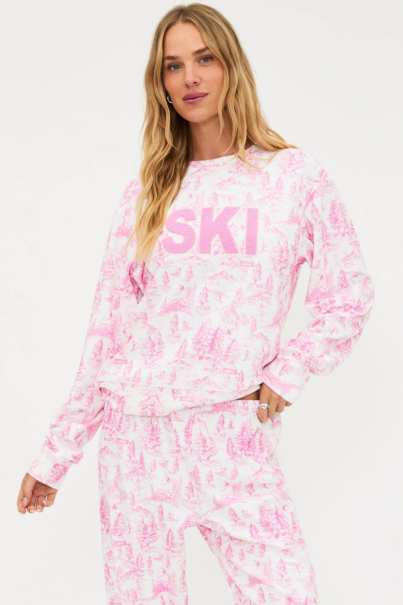 Woman wearing a pink and white tie-dye 'SKI' sweatshirt on a white background