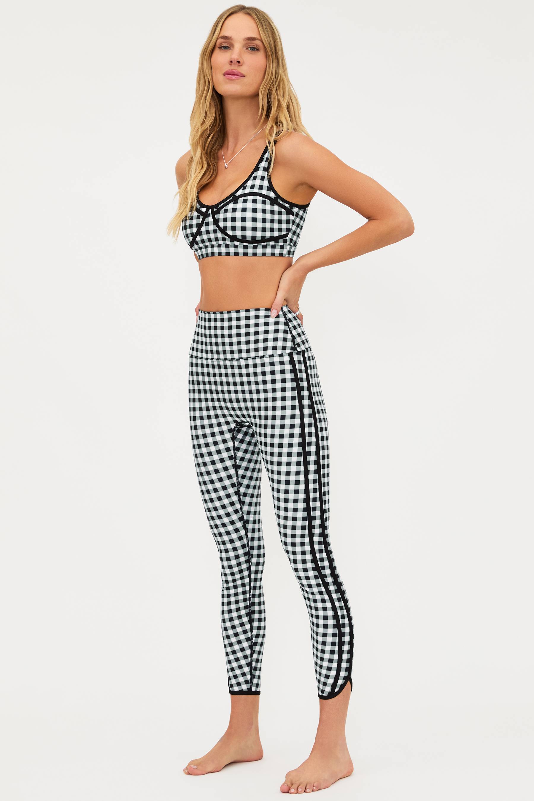 Woman wearing a black and white checkered bikini and leggings set on a white background