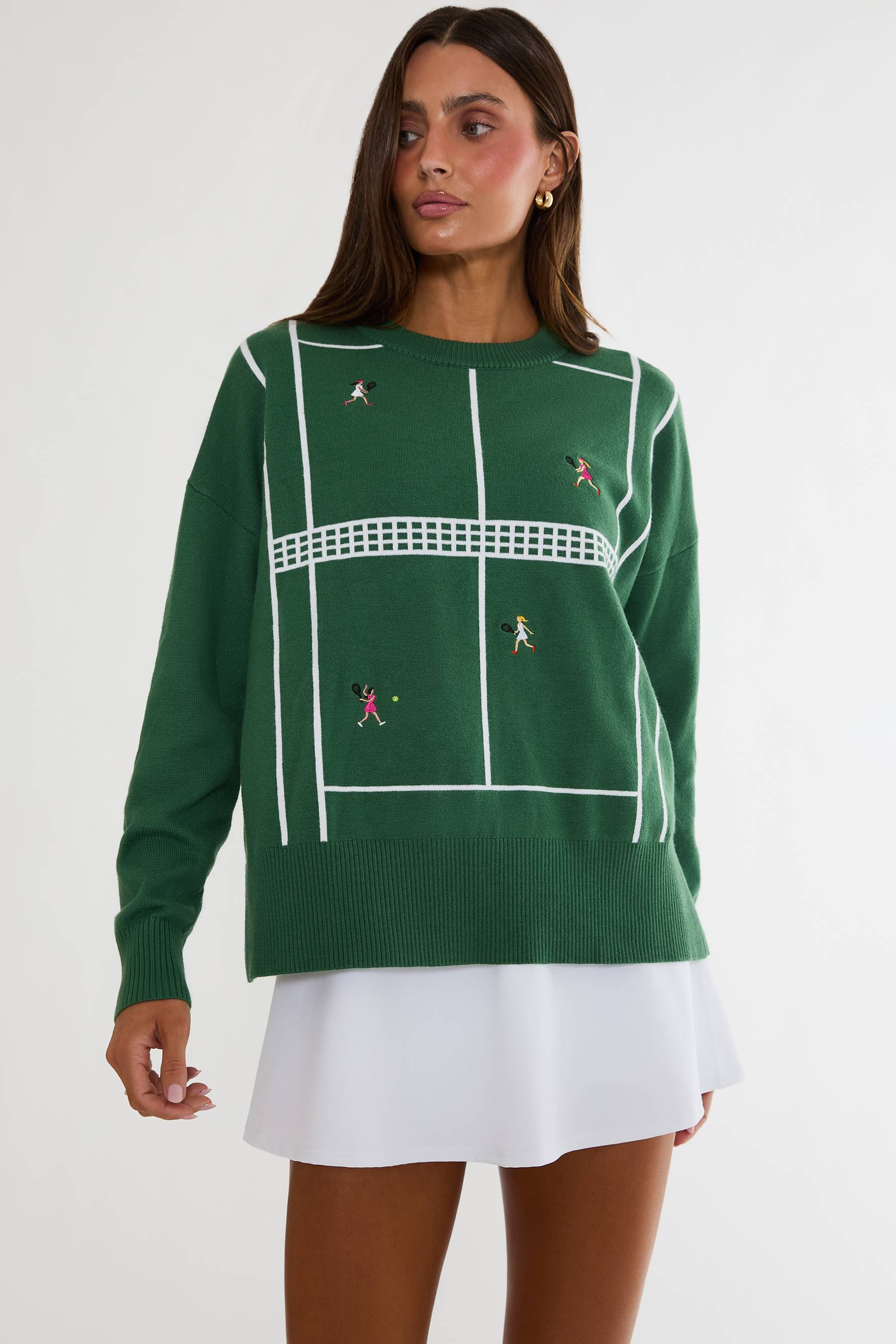 Woman wearing a green sweater with tennis court design on a white background