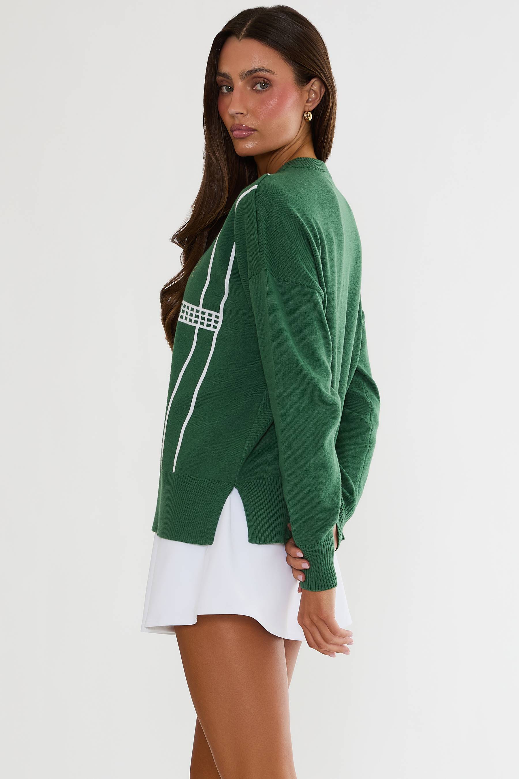 Woman wearing a green sweater with white stripes on a plain background