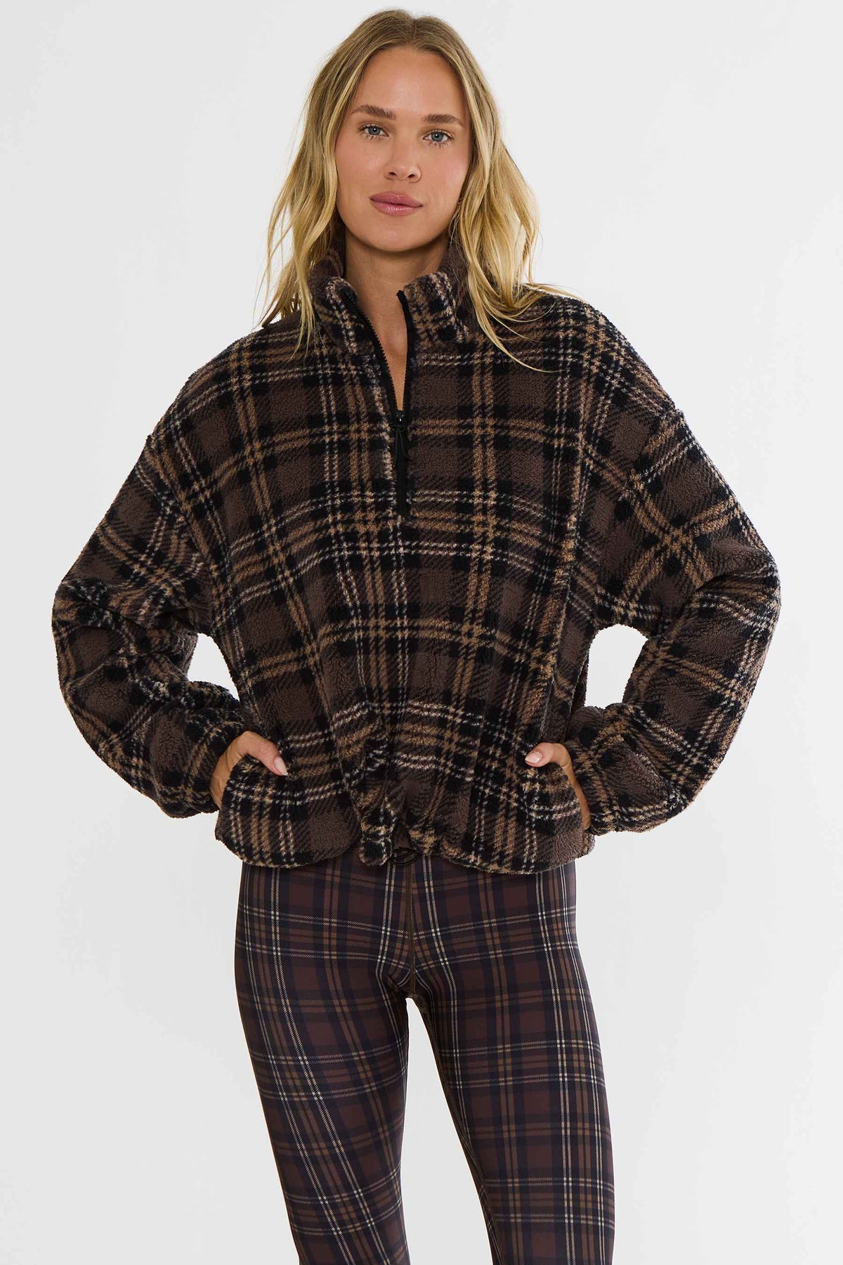 Woman wearing brown plaid sherpa quarter zip jacket. 
