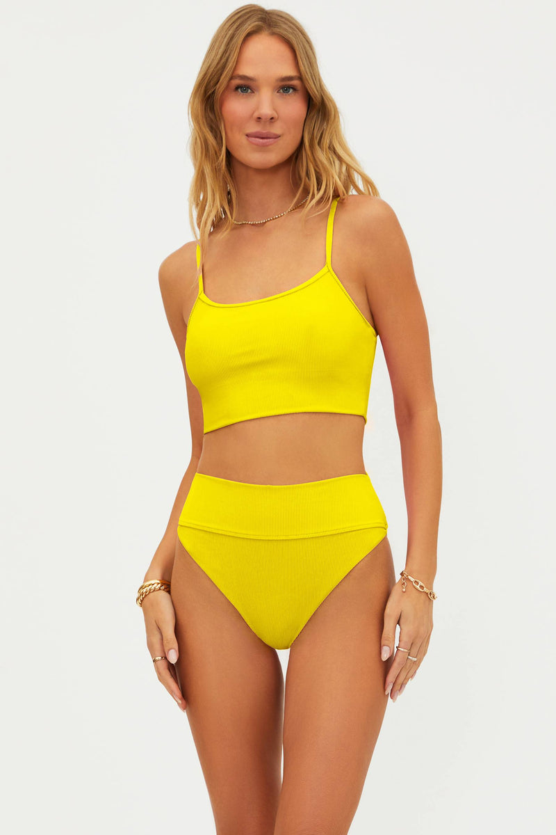 Woman wearing a bright yellow bikini set on a white background