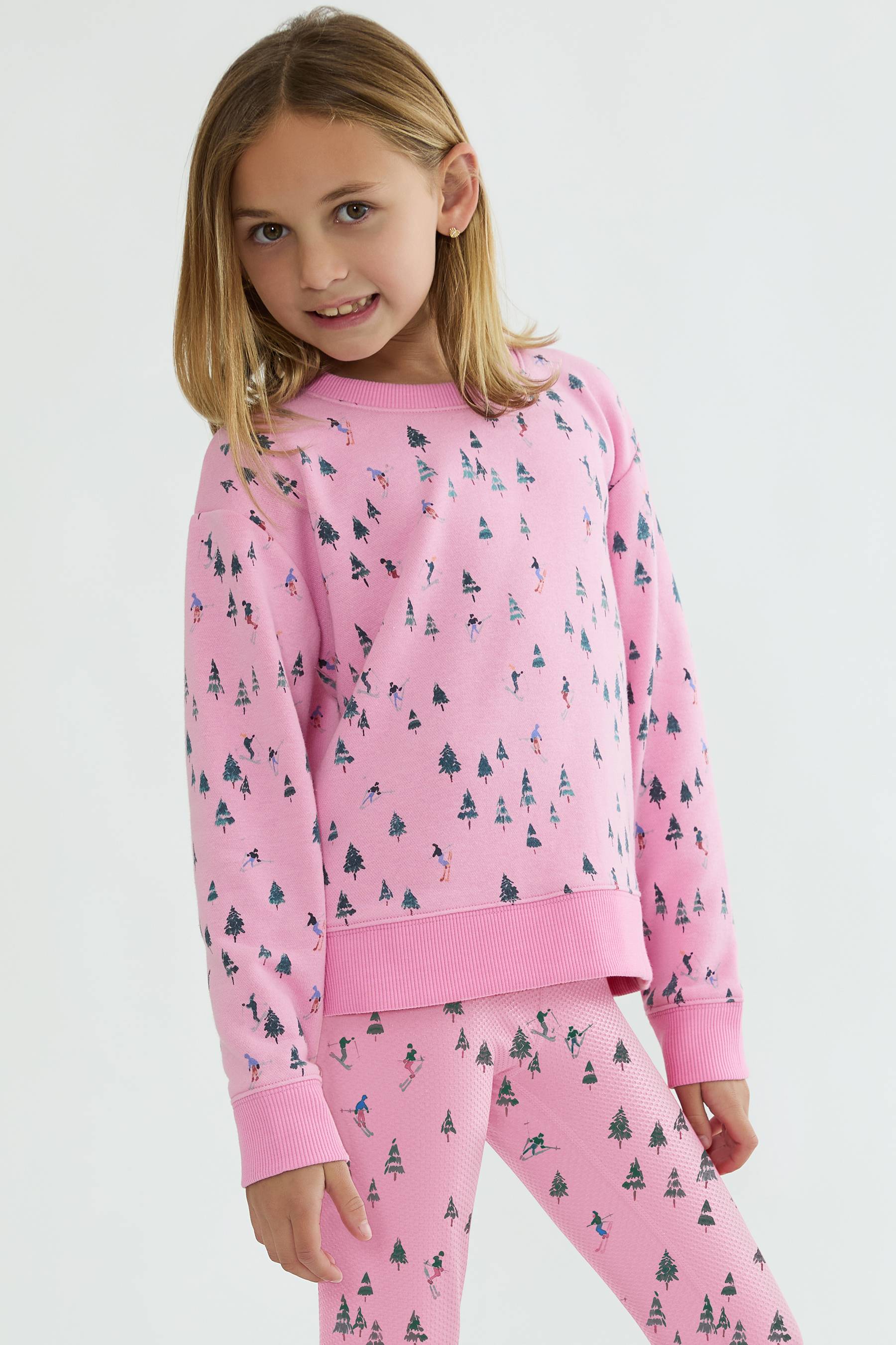 Young girl wearing pink pajamas with a tree pattern on a white background