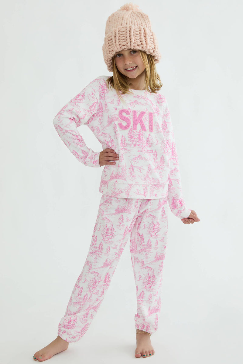 Child wearing pink 'SKI' pajama set and matching hat on a white background