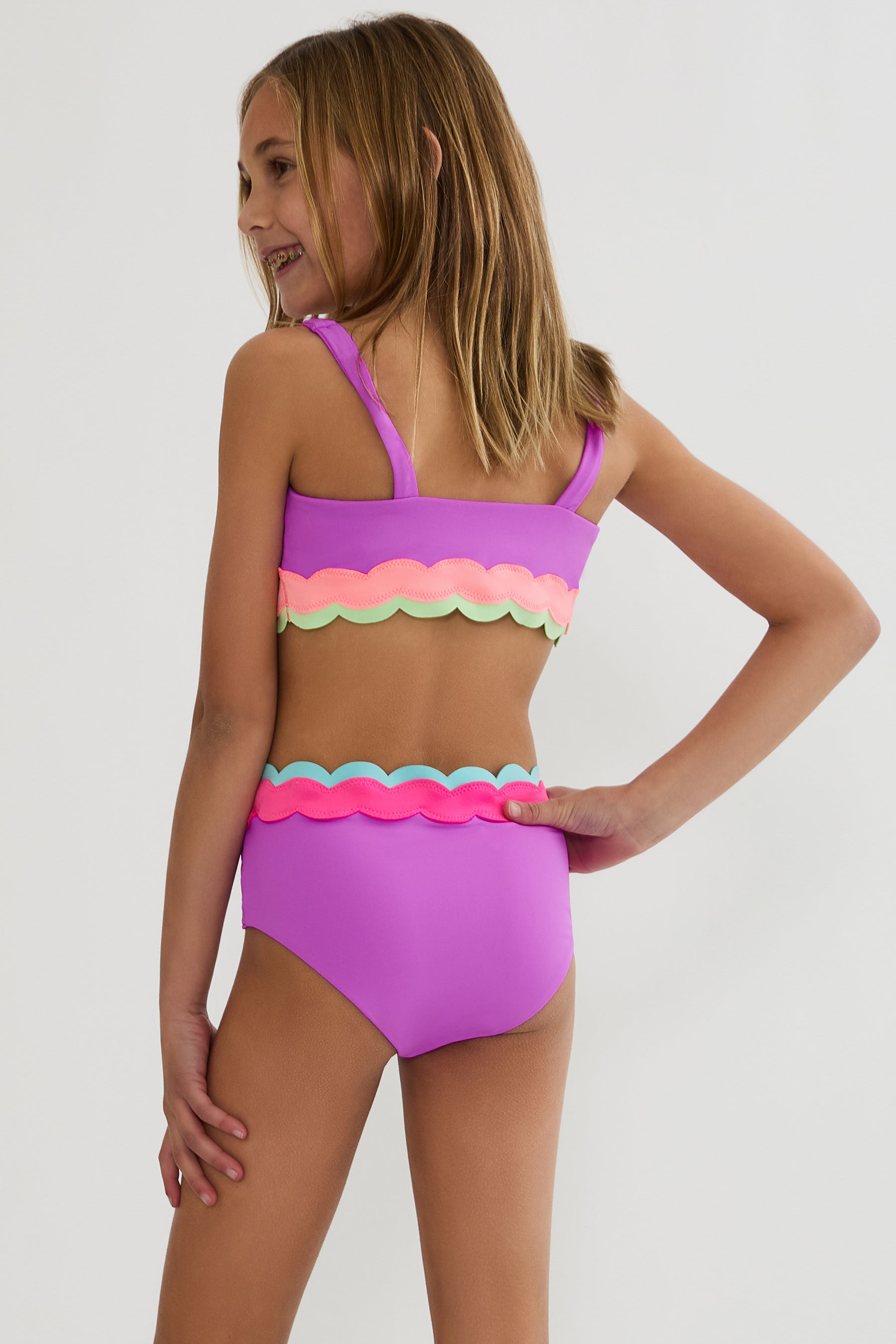 Young girl wearing a colorful two-piece swimsuit on a white background
