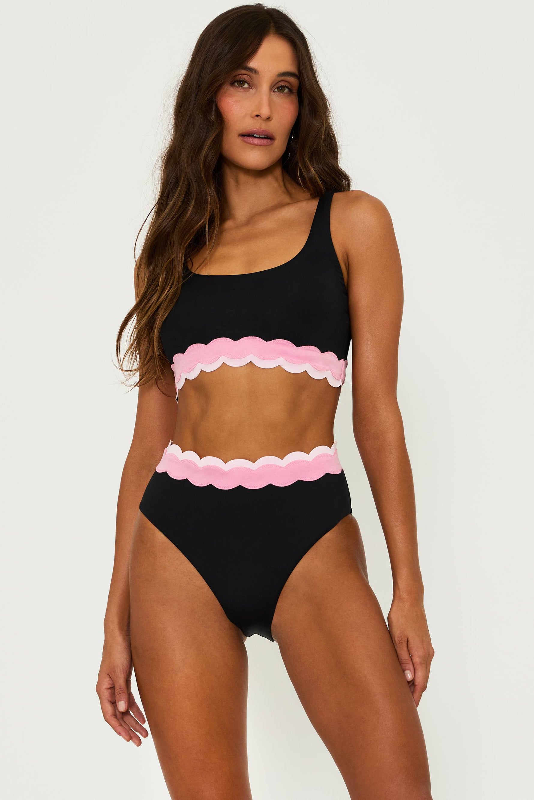 black bralette style swim top with pink contrast wavy trim and a black high waist bottom with pink wavy trim and the top of the waist band