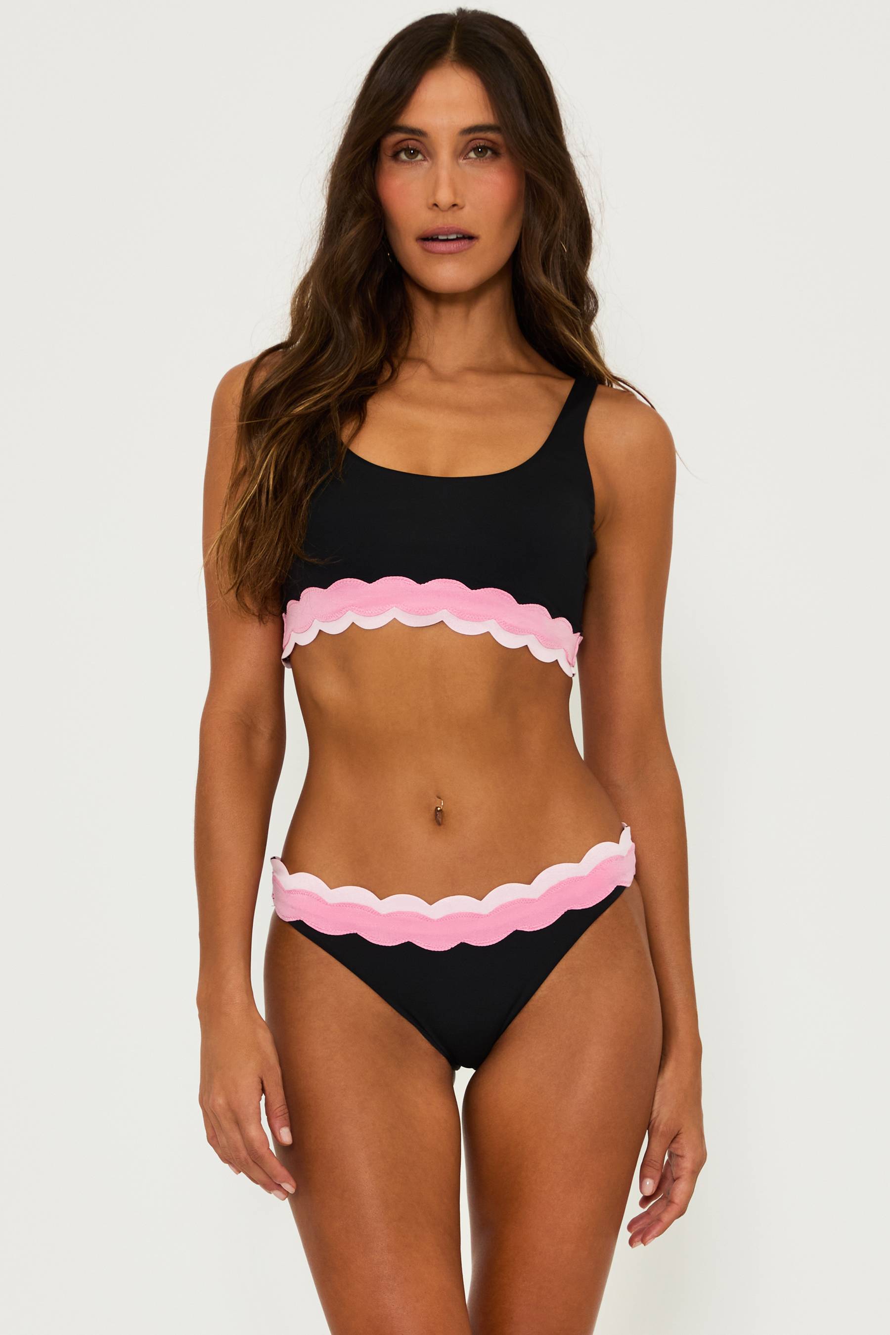 black bralette style swim top with pink contrast wavy trim and a black high waist bottom with pink wavy trim and the top of the waist band