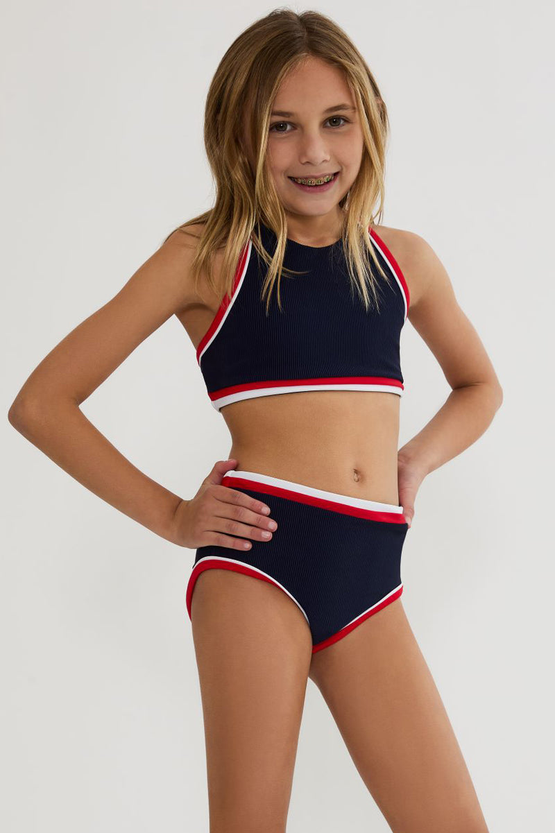 Young girl wearing a black and red bikini with white accents on a plain background