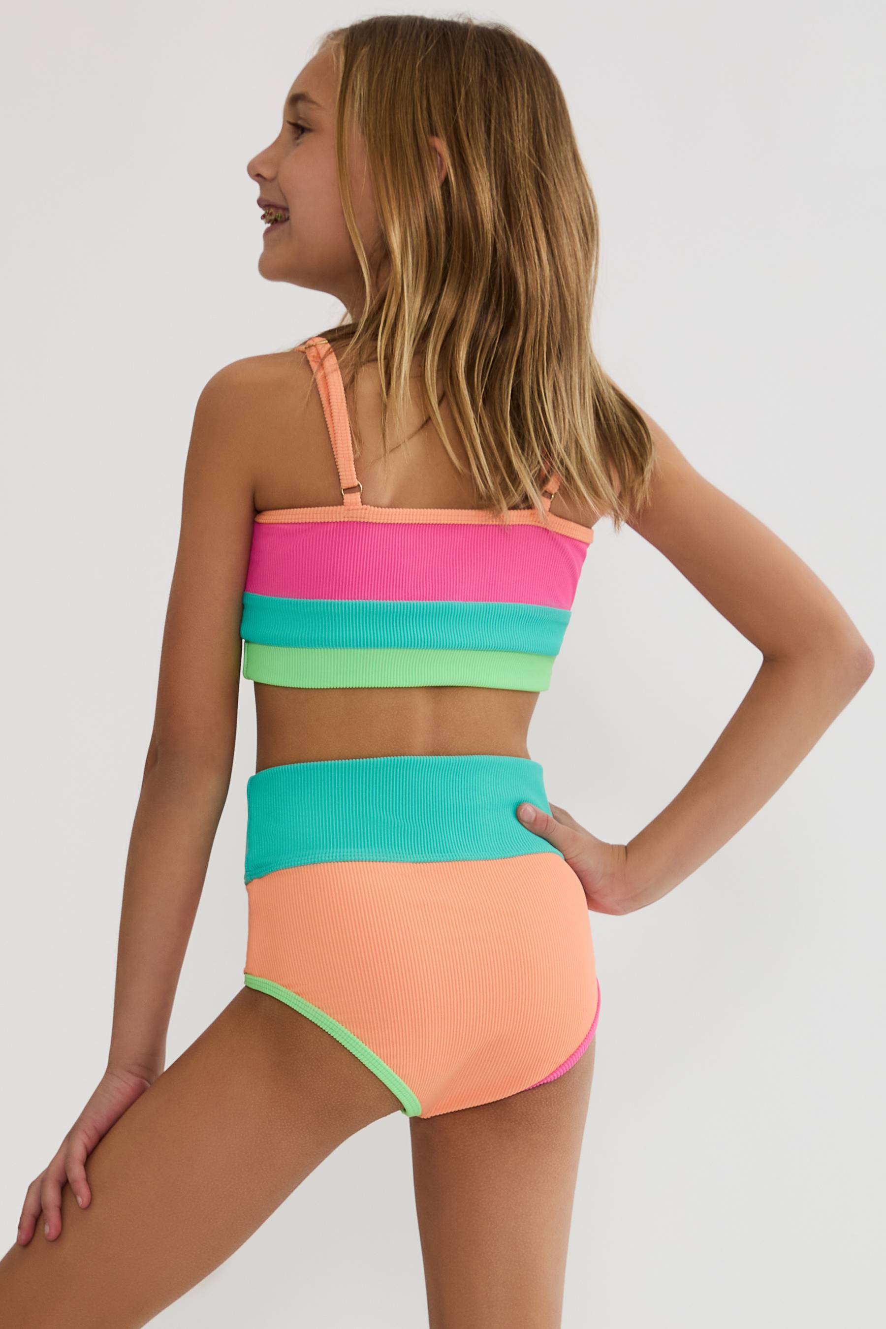 Woman wearing a colorful striped bikini set on a plain background