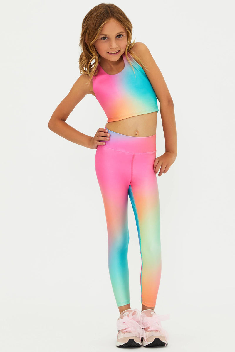 Young girl wearing a colorful rainbow outfit on a white background