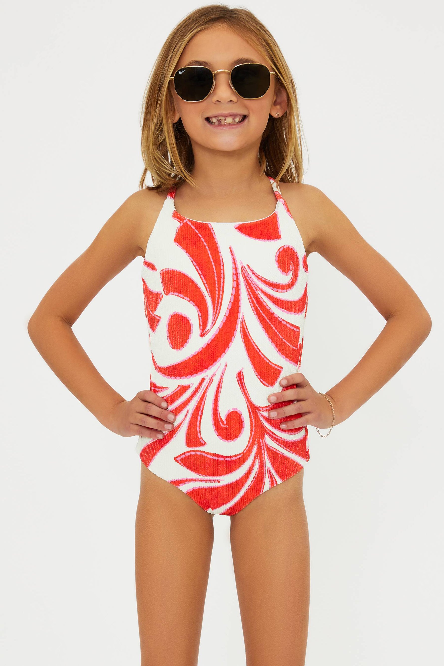 Young girl wearing a red and white patterned swimsuit on a plain background