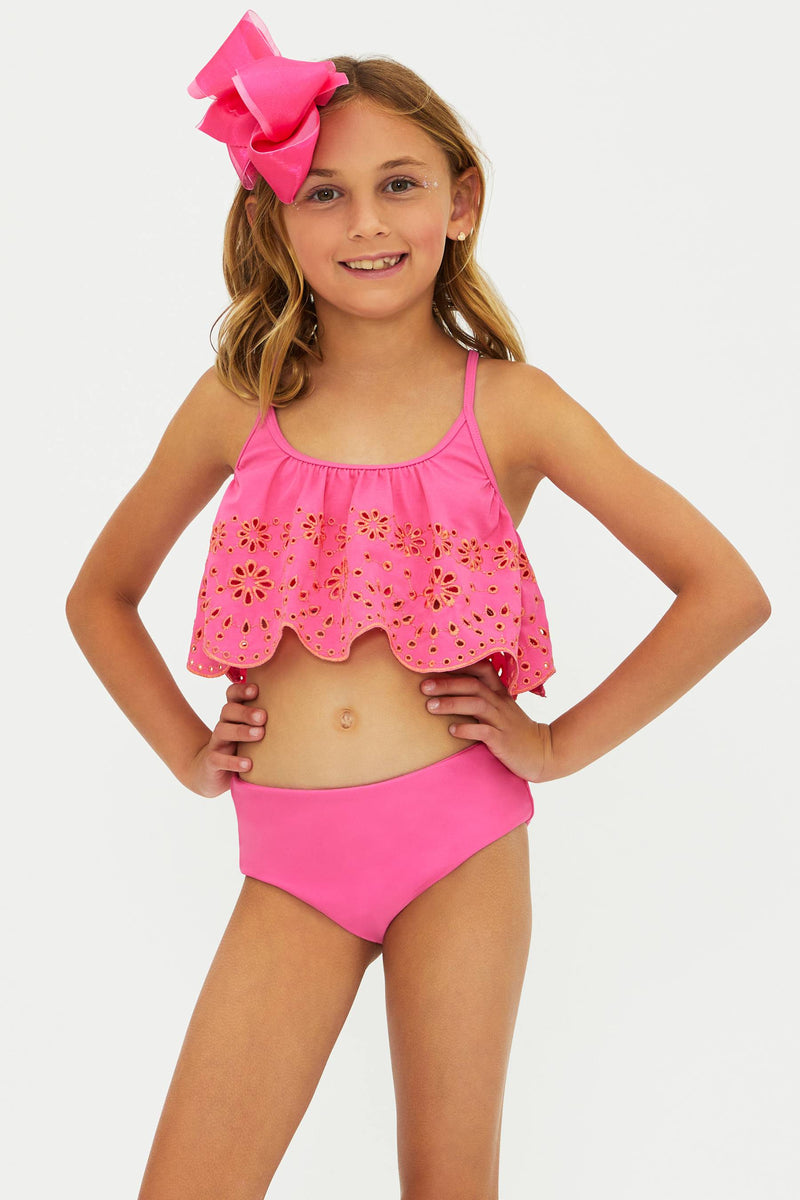 Young girl wearing a pink bikini with a matching headband on a white background