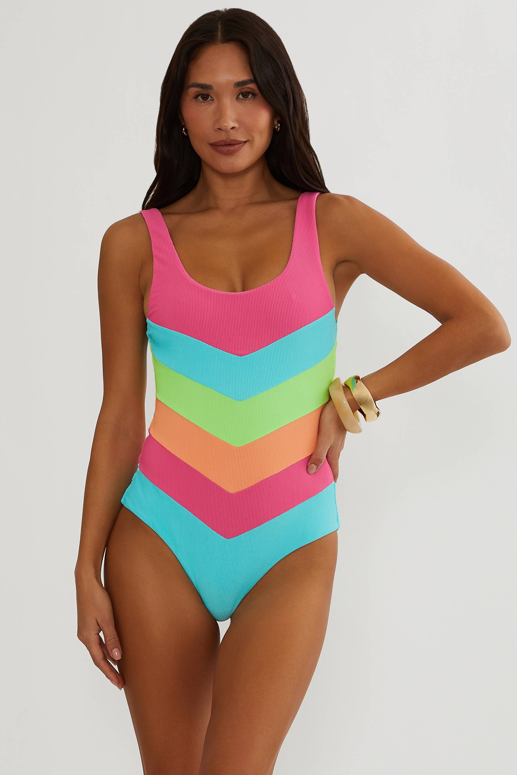 Woman wearing a colorful chevron-patterned swimsuit on a white background