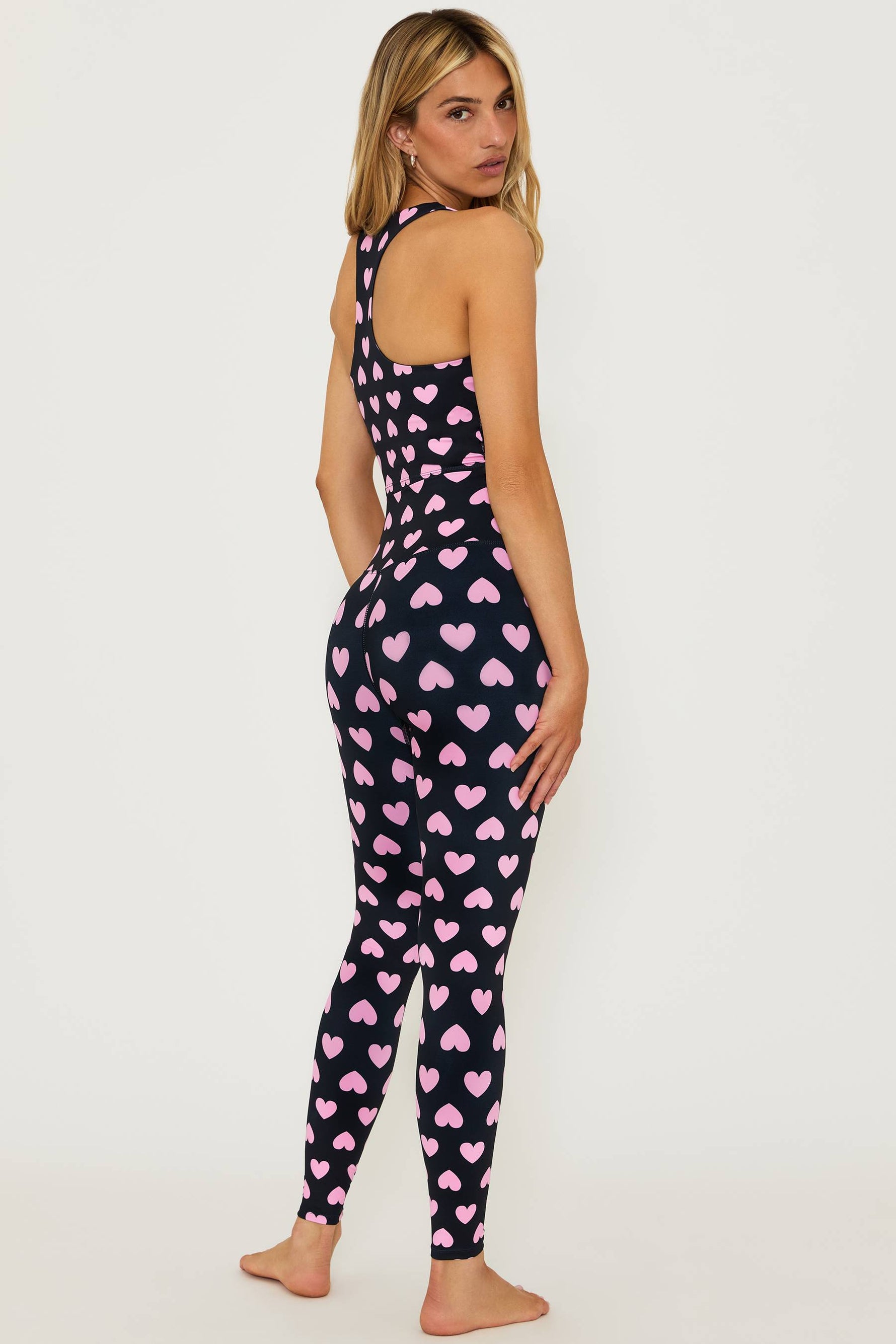 black full length high waisted leggings with pink hearts printed all over and a matching black crop top that is black with pink hearts