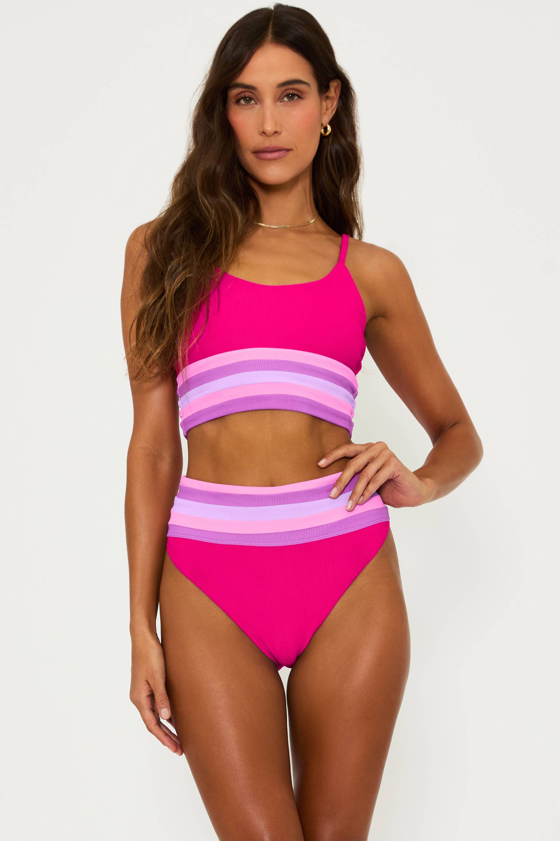 high waisted magenta swim bottom with pink and purple stripes at the top hem and a matching bralette style swim top with pink and purple strips at the bottom hem